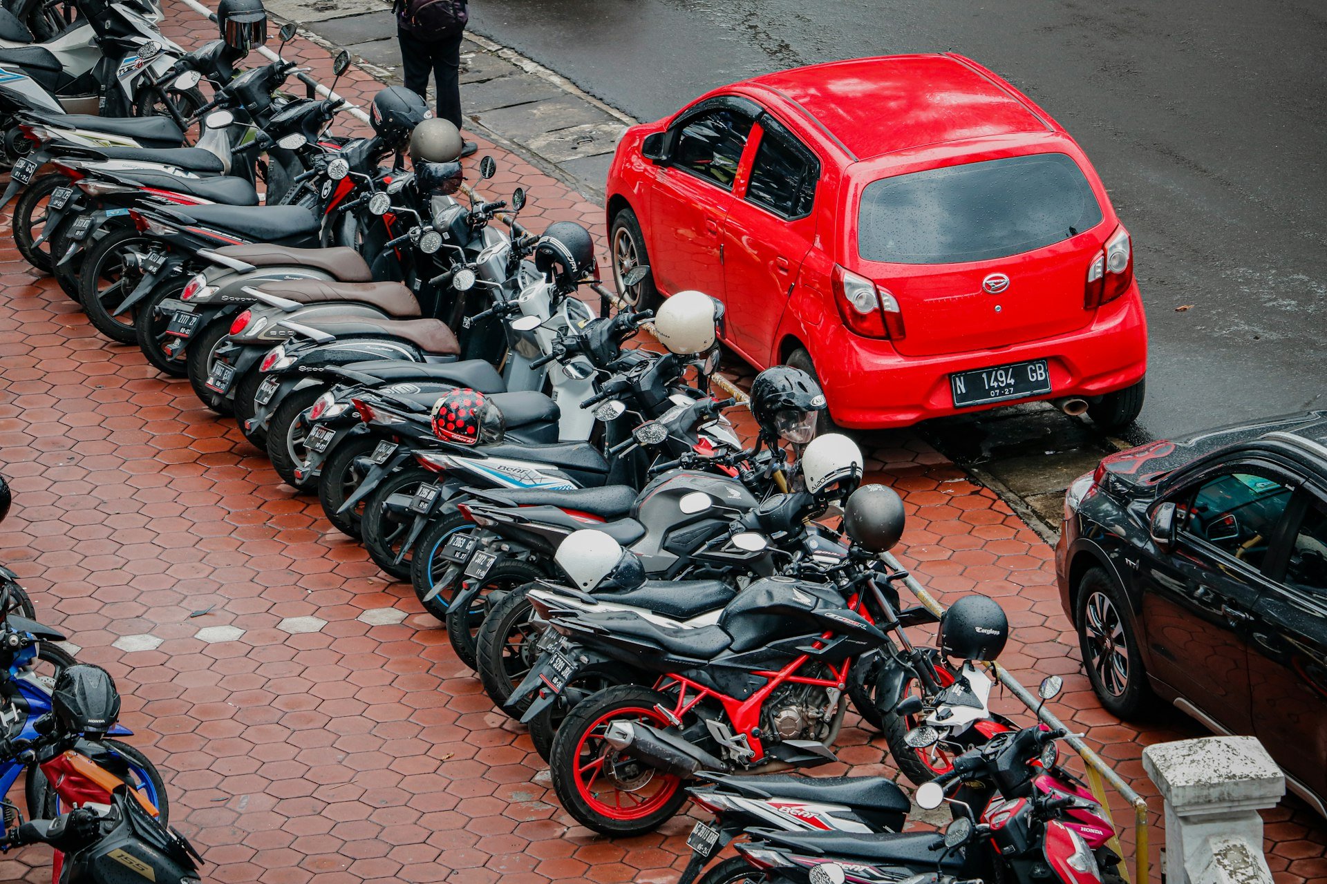 a row of motorcycles parked next to a red car